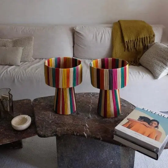Two colorful striped lamps on a stone coffee table in a living room.