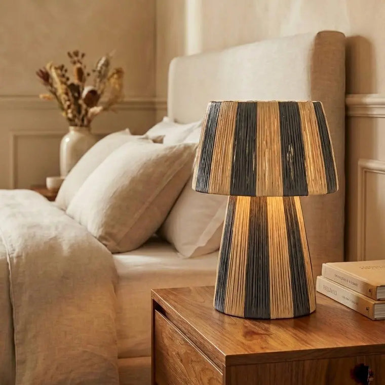 Wooden table lamp on a nightstand next to a bed in a bedroom setting