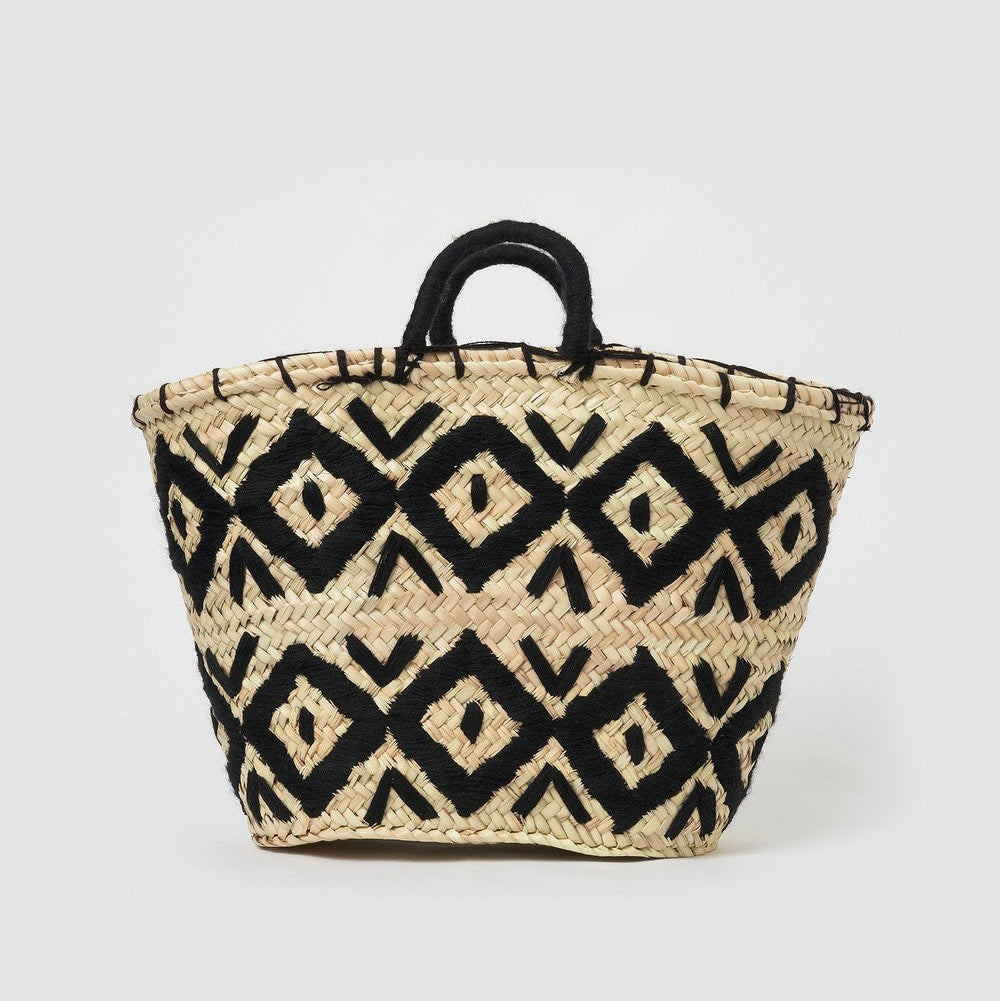 A woven straw tote bag with a black geometric diamond pattern and black rope handles, photographed on a light gray background.