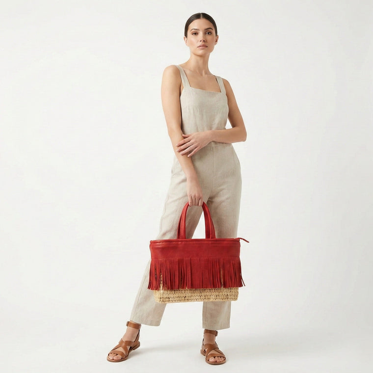 Woman holding a red handbag with fringe details on a white background