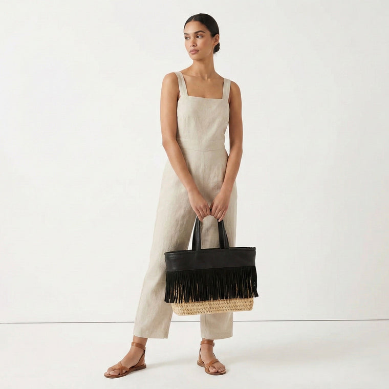 Woman holding a black fringed bag against a white background