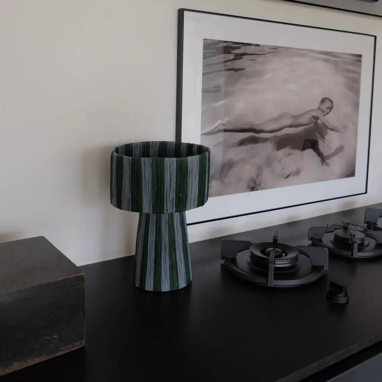 Decorative vase on a table with a framed artwork in the background