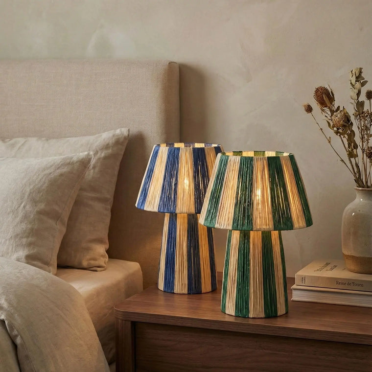Two striped lamps on a wooden nightstand next to a bed.