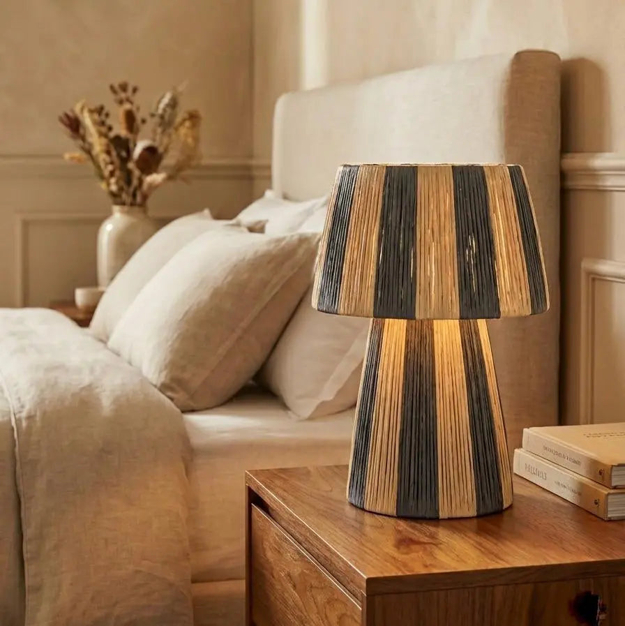 Wooden table lamp on a nightstand next to a bed in a bedroom setting