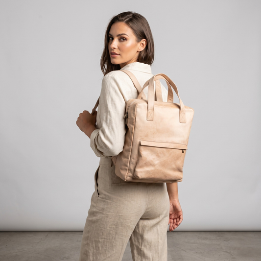 Woman wearing a beige backpack against a plain background