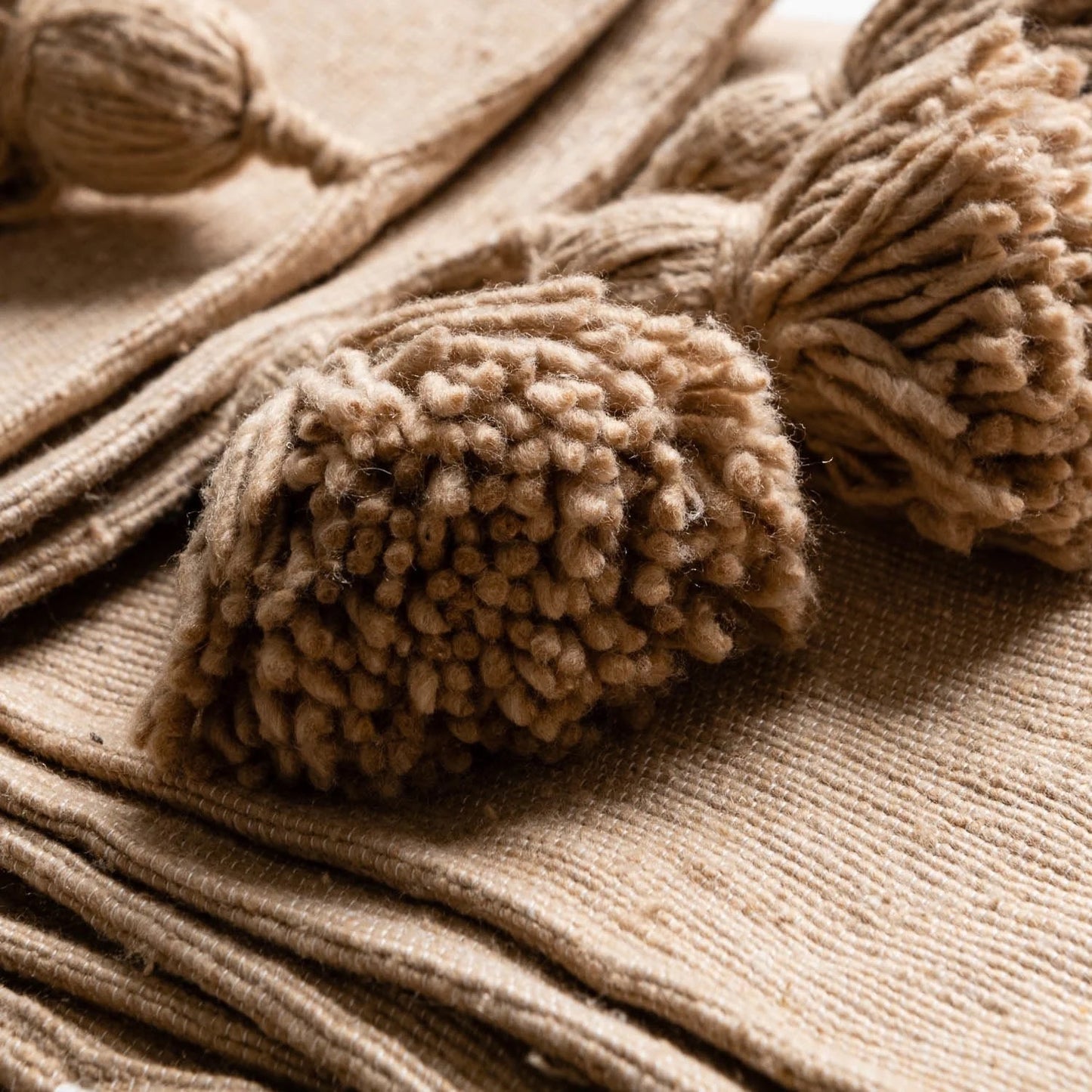 Close-up of beige tassels on a textured fabric background