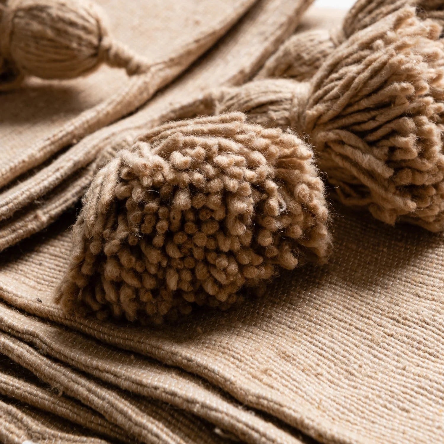 Close-up of beige tassels on a textured fabric background
