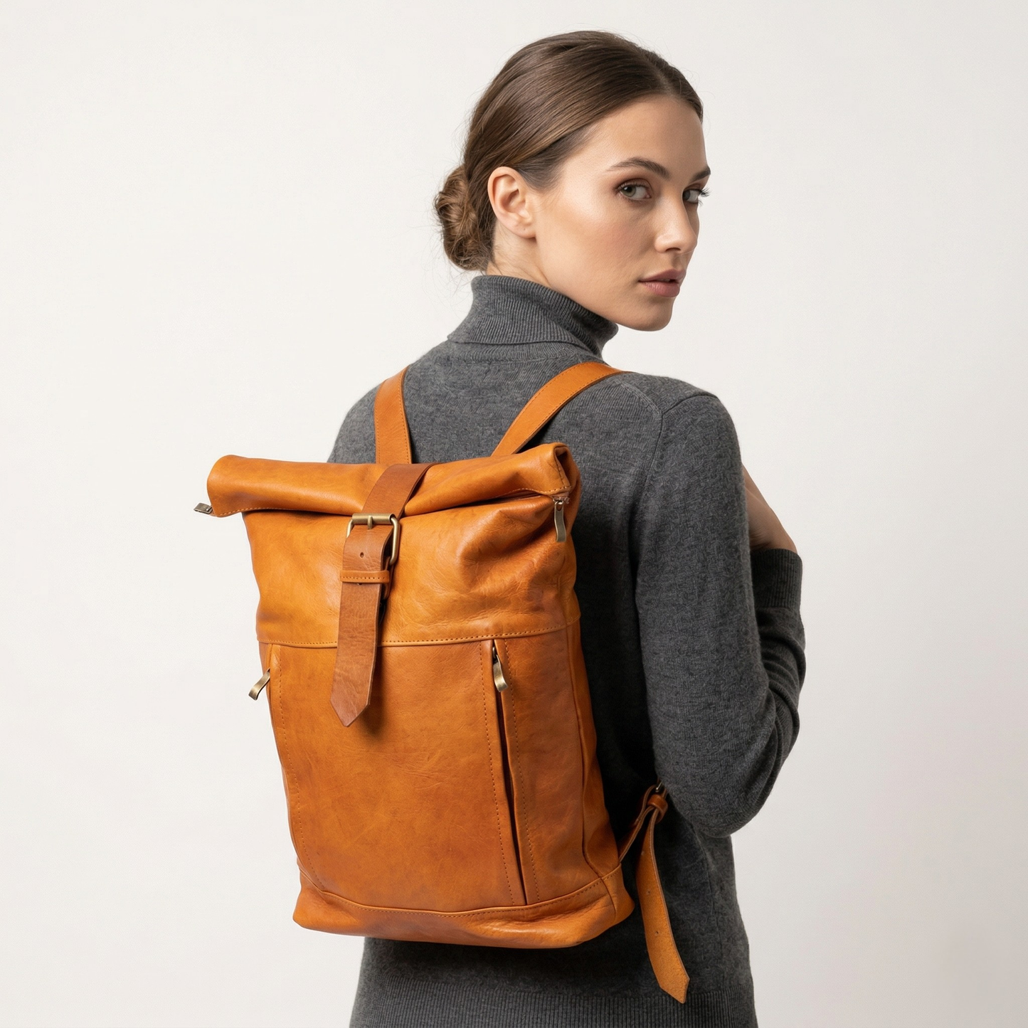 Woman wearing a brown leather backpack against a plain background