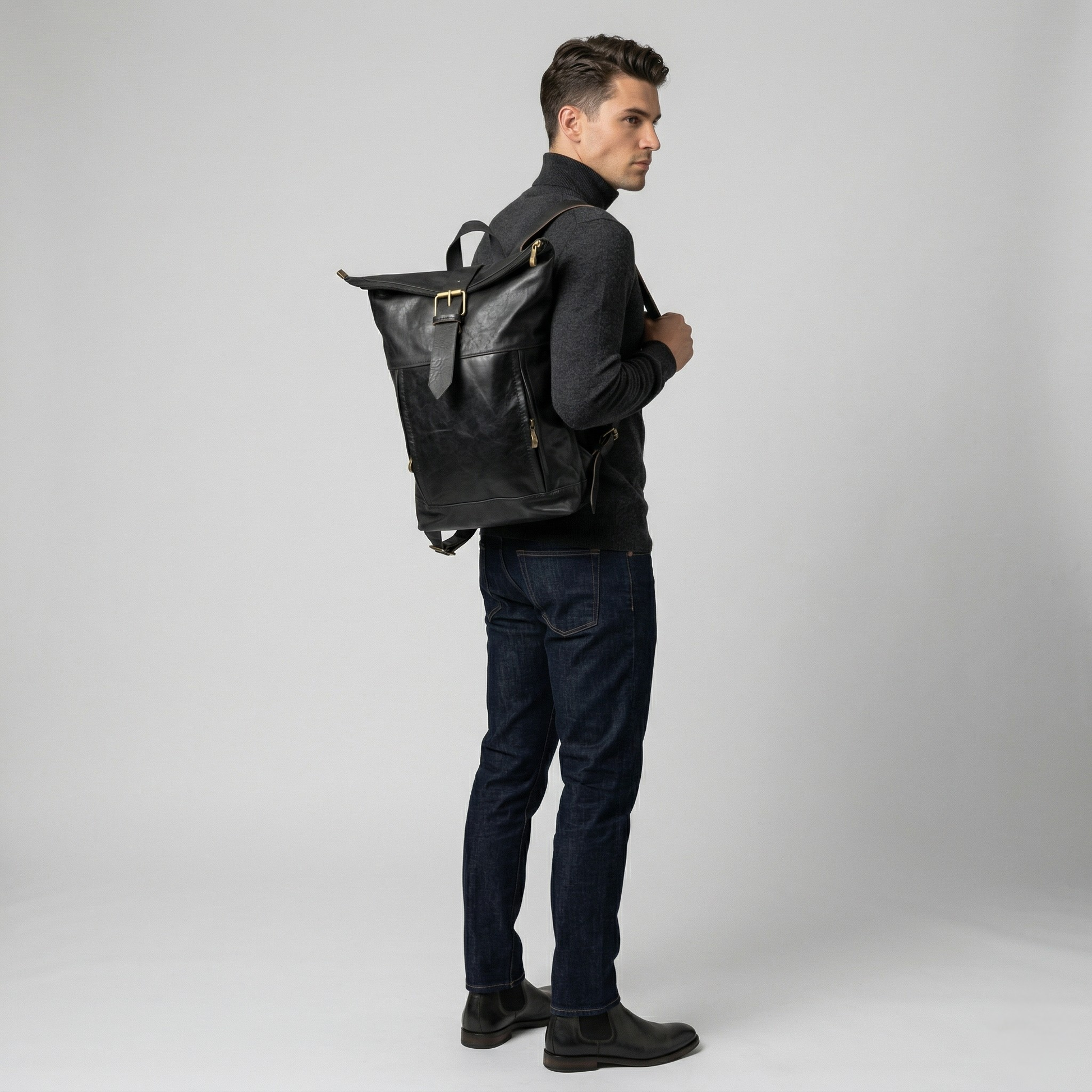 Man wearing a black leather backpack on a plain background