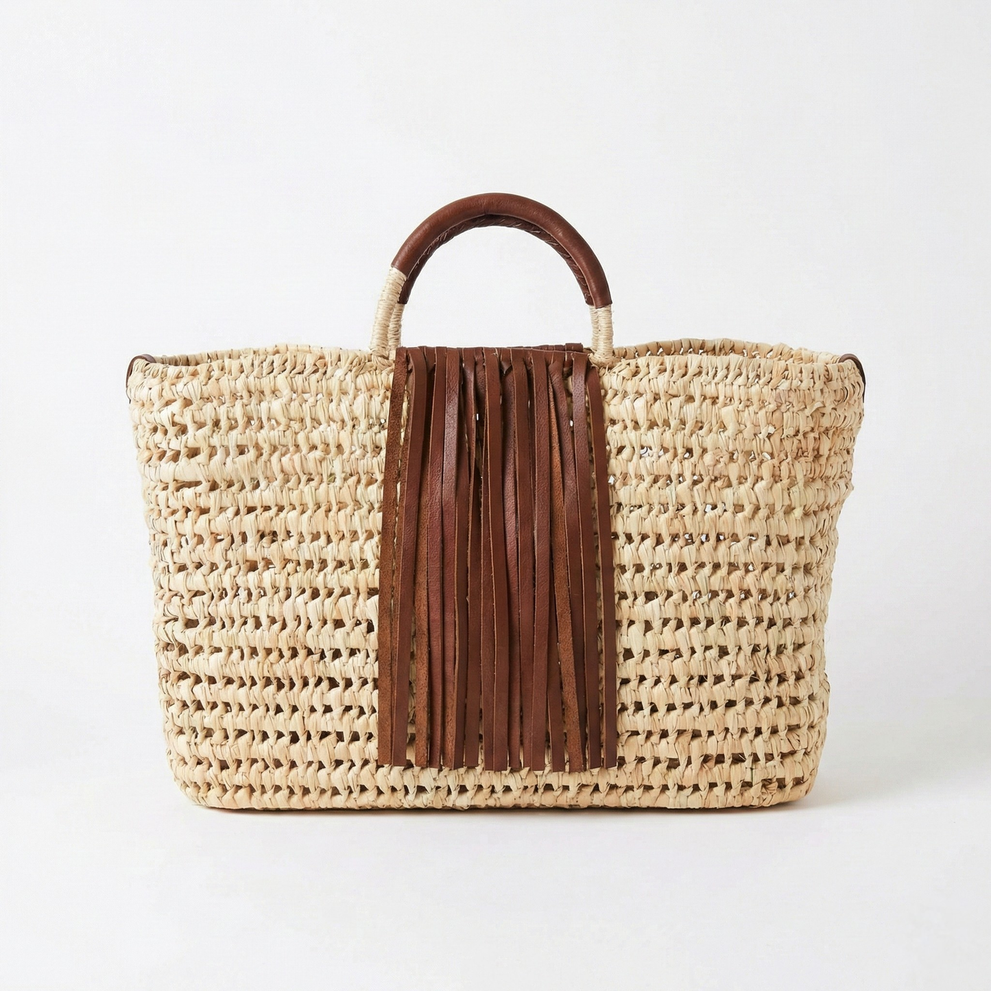 Woven bag with brown leather fringe and handle on a white background