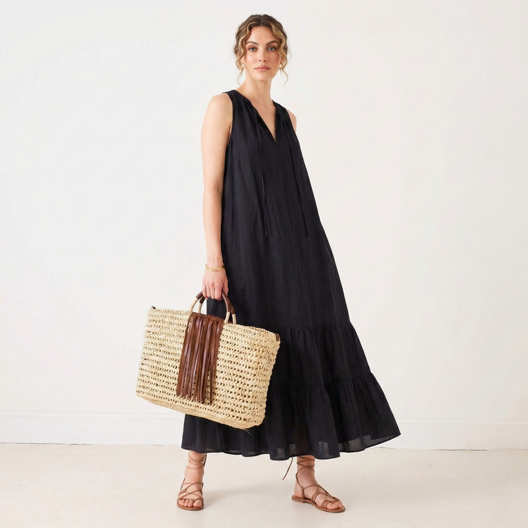 Woman in a black dress holding a straw bag on a white background