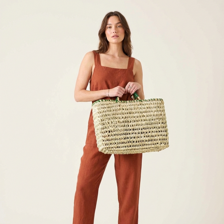 Woman holding a woven bag against a plain background