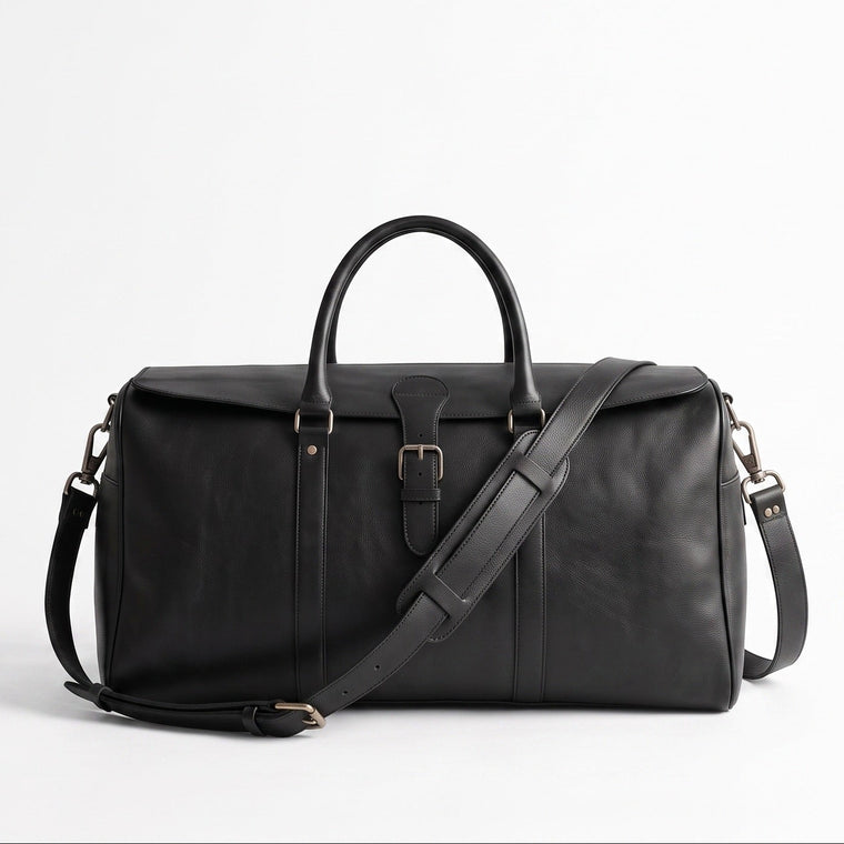 A black leather duffel bag with dual top handles, a front buckle closure, and an adjustable shoulder strap, photographed on a clean white studio background.