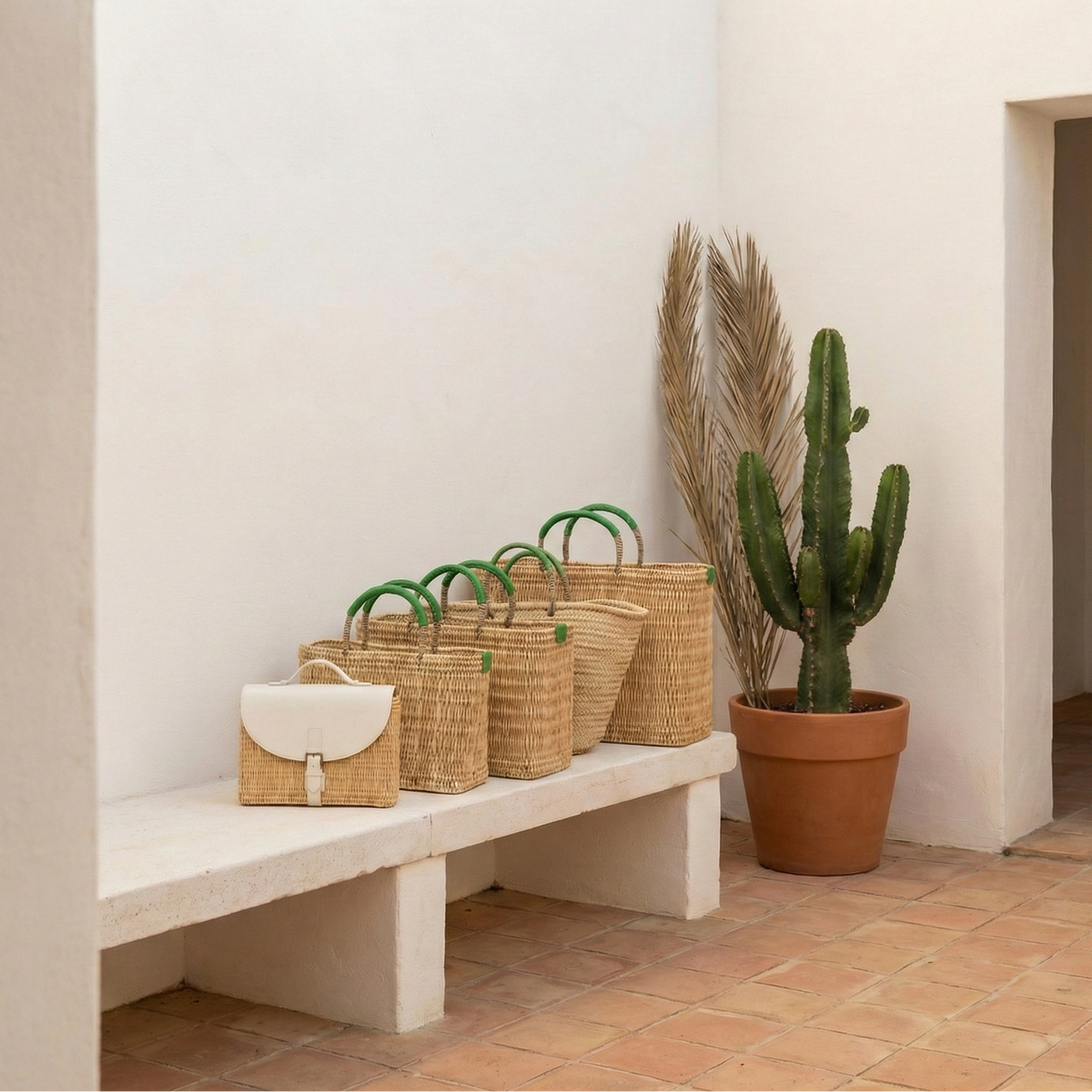 Wicker bags on a bench next to a potted cactus in a minimalistic setting