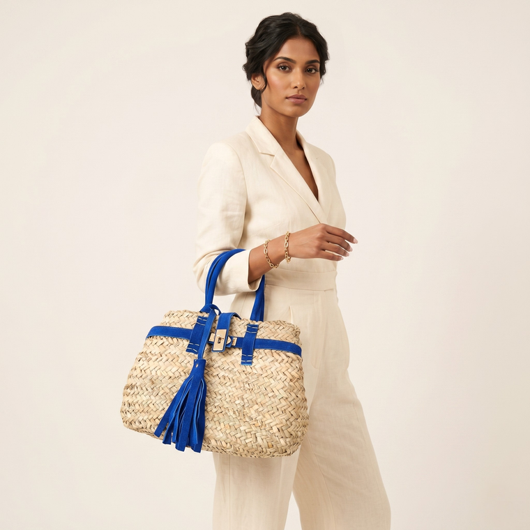 Woman holding a straw bag with blue straps against a plain background
