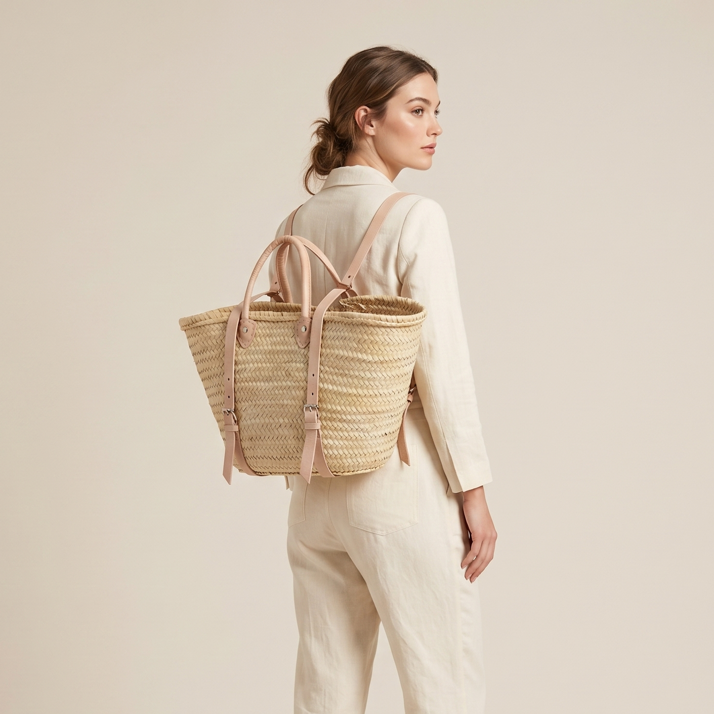 Woman wearing a straw backpack on a plain background