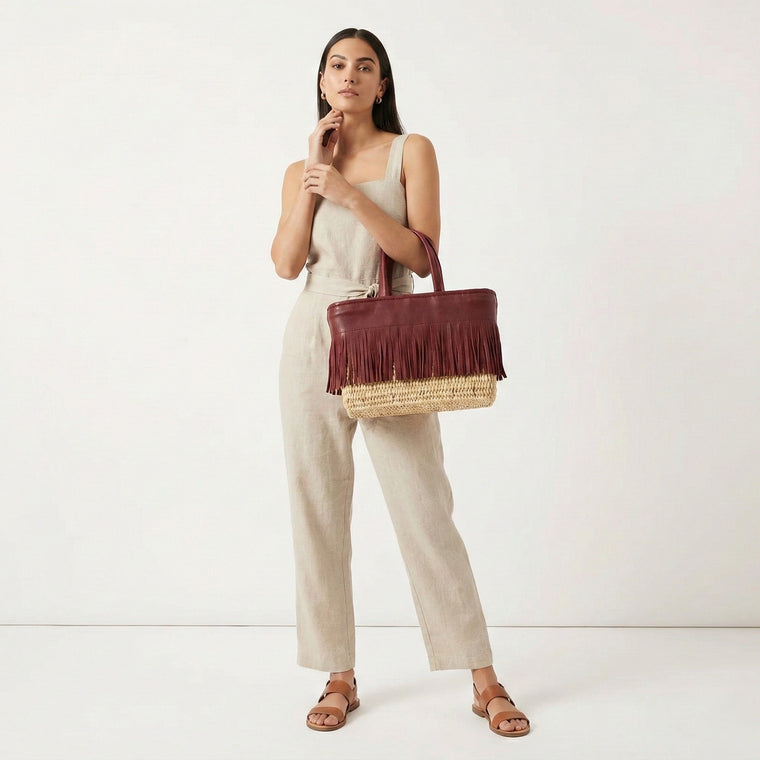 Woman holding a brown leather handbag with a straw handle on a white background