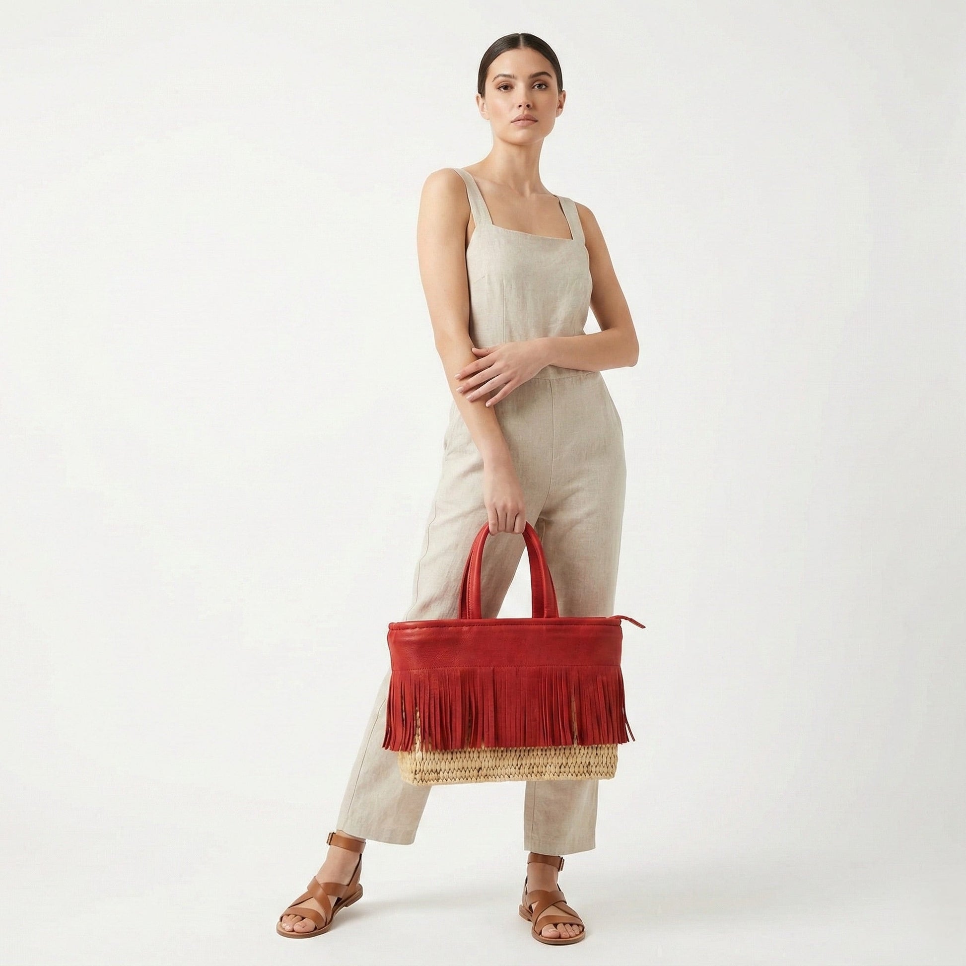 Woman holding a red handbag with fringe details on a white background