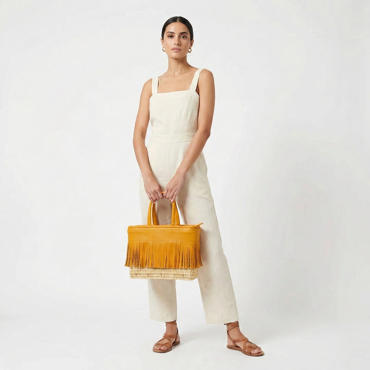 Woman holding a mustard yellow handbag against a white background