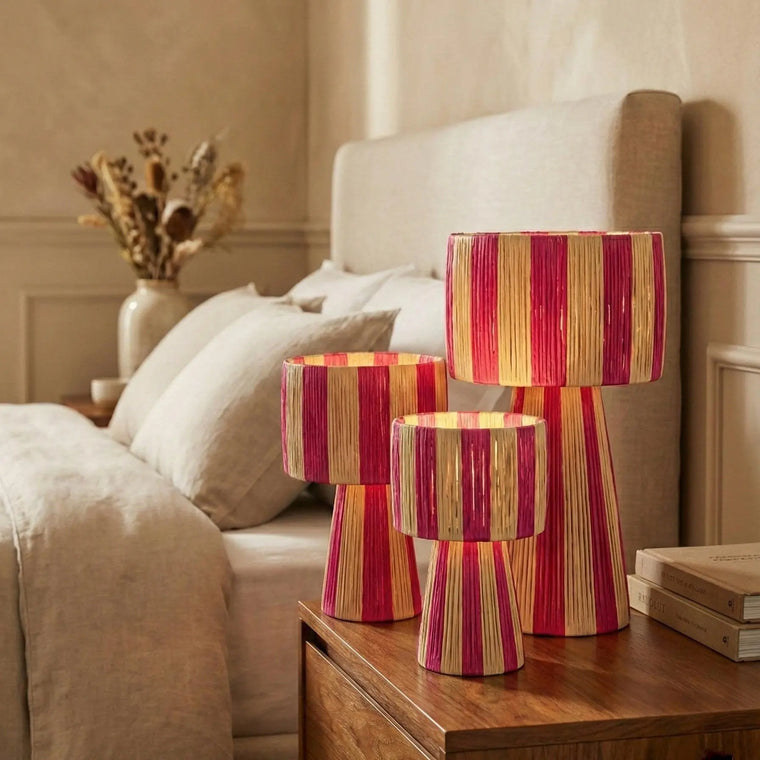 Three striped lamps on a wooden nightstand in a bedroom setting.