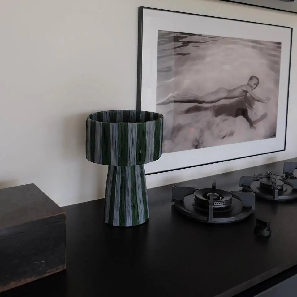 Decorative vase on a table with a framed artwork in the background