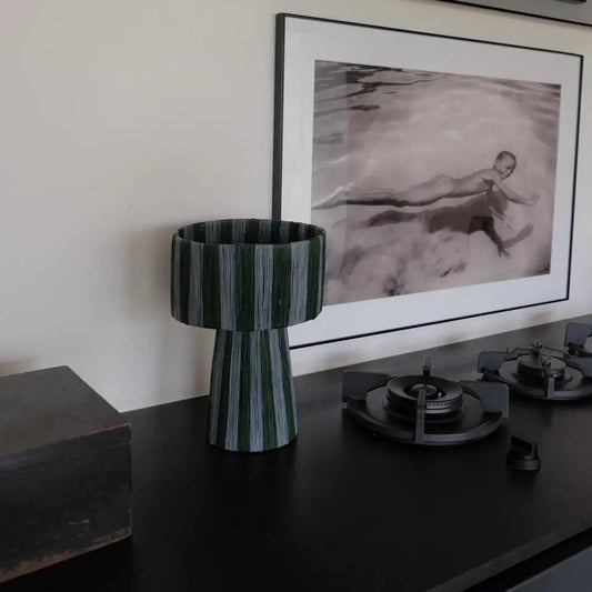 Decorative vase on a table with a framed artwork in the background