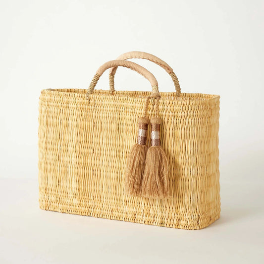 Woven handbag with tassels on a light background